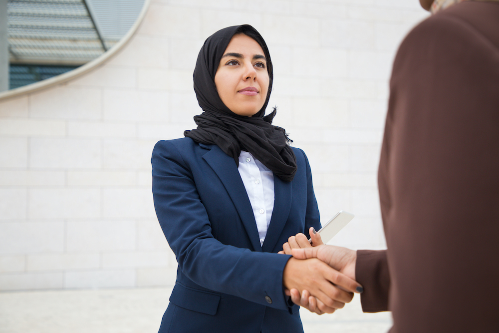 Two individuals shaking hands in a professional setting, symbolizing corporate migration